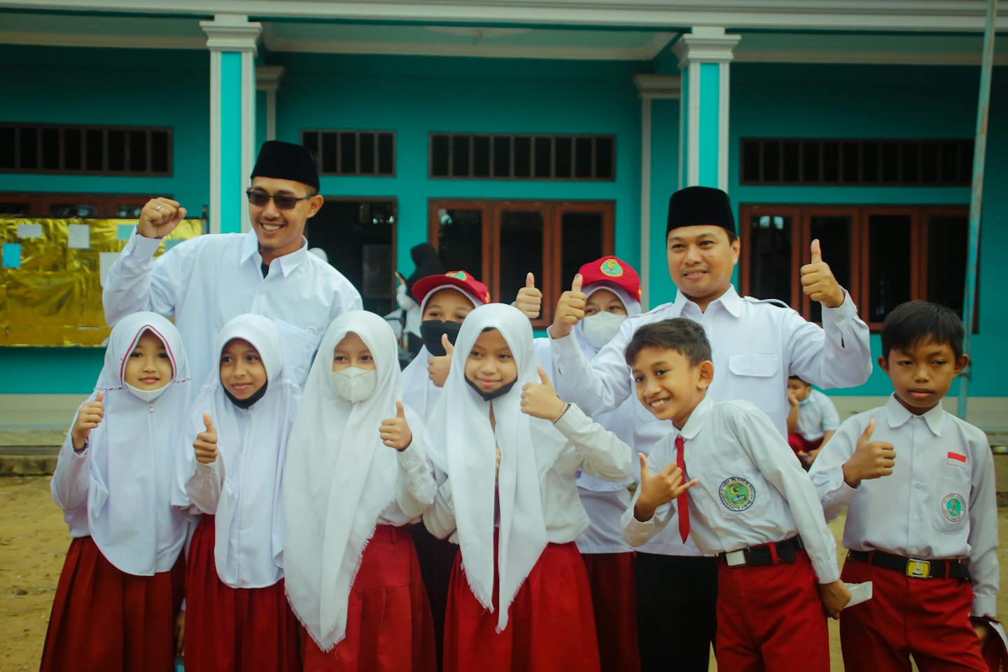 Students and teachers in school uniforms pose outside a building.