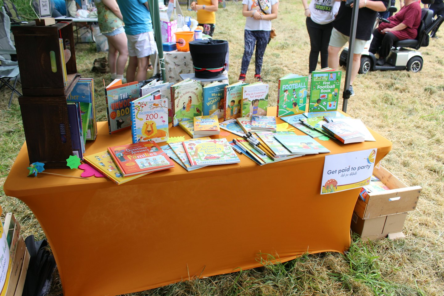 Childrens books displayed on a table at an outdoor market.