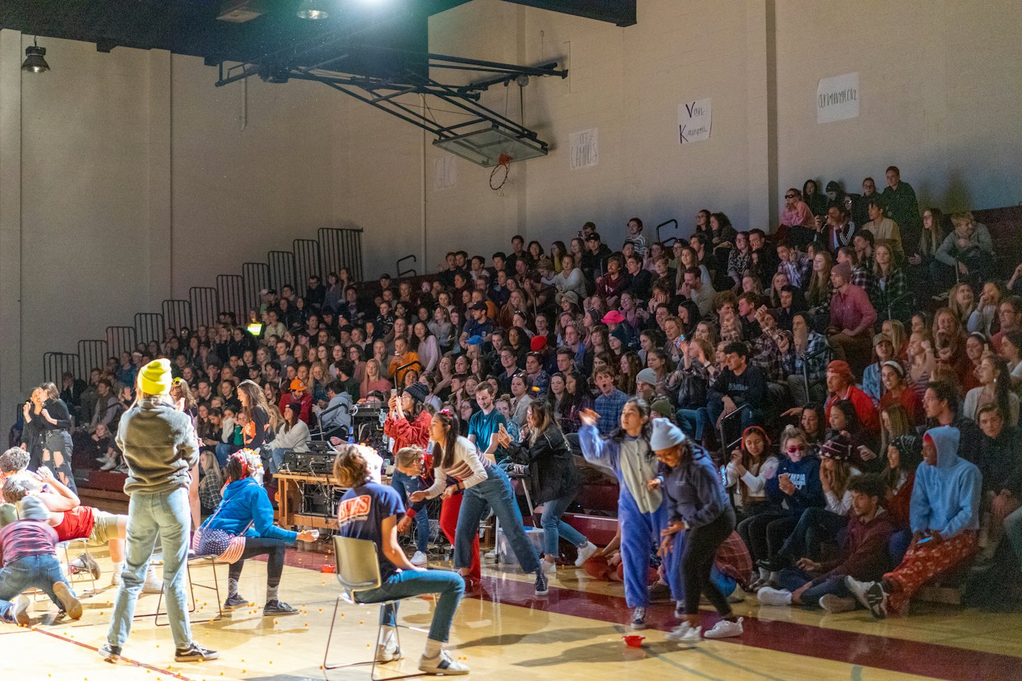 Students gather on a gymnasium floor during an indoor event.