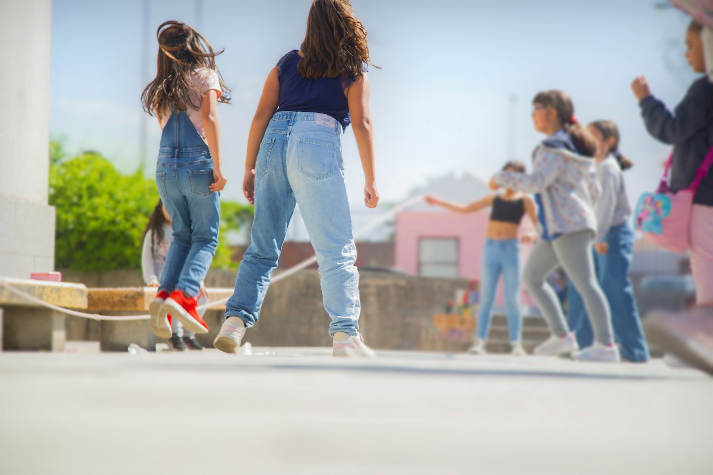 Children jumping joyfully on a sunny day outside.