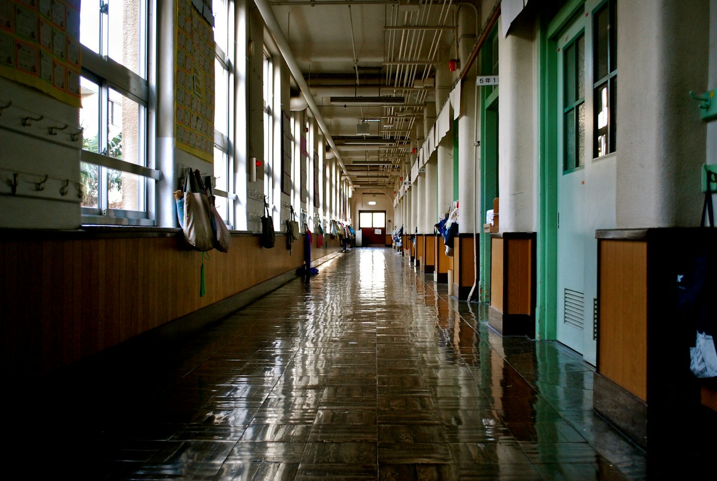 Empty school hallway with lockers and sunlight on the floor.